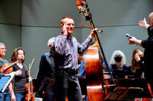 Featured soloist Stephen Schermer smiles at the audience during Saturdays public dress rehearsal with the Port Angeles Symphony Orchestra, which brings musicians from across and beyond the North Olympic Peninsula to the Port Angeles High School Performing Arts Center. The symphony celebrated its 90th anniversary over the weekend with the world premiere of the specially commissioned Concerto for Double Bass and Orchestra by Seattle composer Sarah L. Bassingthwaighte. (Diane Urbani de la Paz for Peninsula Daily News)