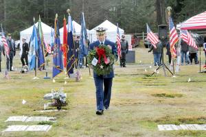 Cmdr. Brian Tesson, commanding officer of the U.S. Coast Guard Cutter Active, carries a wreath for the grave of Coast Guard veteran Harold Hanusa, who served during World War II, during Saturdays Wreaths Across America ceremony at Mount Angeles Memorial Park in Port Angeles. The event, part of a national initiative to honor veterans of military service, saw individual branches of the military recognized during the ceremony followed by the placement of more than 2,300 wreaths for servicemen and women at six cemeteries across the North Olympic Peninsula. (Keith Thorpe/Peninsula Daily News)