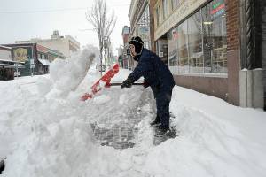 Alan Turner, co-owner of Port Book and News in downtown Port Angeles, shovels snow from in front of his business on Tuesday morning after most of the North Olympic Peninsula was blanketed in the overnight hours. (Keith Thorpe/Peninsula Daily News)