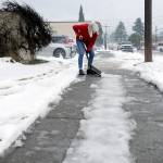 Barb Maynes, a member of First United Methodist Church in Port Angeles, breaks up ice on the sidewalk on the Laurel Street side of the church on Saturday. Warming temperatures and rain were helping to melt nearly a foot of snow that had fallen earlier in the week, but remaining accumulated ice required physical attention in many locations. (Keith Thorpe/Peninsula Daily News)