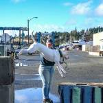 Natalie Calcote of Port Townsend exercises her dog, Davy Jones, by jumping over concrete barriers used to close off Washington Street, the main road through the Port Townsend Boat Haven Marina, which remained closed on Wednesday after severe flooding by the high tide and tidal surge on Tuesday. The drains were full and it was unknown what the effect of the anticipated 9.5-foot high tide at 9:44 a.m. today would be on road conditions. The road may be re-opened this afternoon during the falling tide. (Steve Mullensky/for Peninsula Daily News)