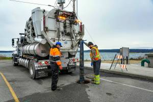 Steve Mullensky/for Peninsula Daily News

Rafe Thornton, left, and Lane Dotson, both with the City of Port Townsend Street, Sewer and Storm department vacuum sewage out of the manhole and into the truck, on Thursday, in order to facilitate repairs to the broken sewer line at Gaines and Water Streets in Port Townsend, on a newly installed sewer line damaged by recent storm and tidal activity.