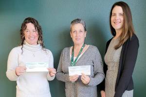 Port Angeles Education Foundation Board President Michelle Turner, on left, presents checks to Michell Gentry, AmeriCorps program director and Kira Acker, Port Angeles School District business and operations director, on right.
