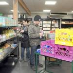 Analise Graziani, manager of The Market at the Port Angeles Food Bank, left, and Adam Frandsen, a food bank staff member with Americorps, stock shelves at The Market before opening to the public on Thursday. (KEITH THORPE/PENINSULA DAILY NEWS)