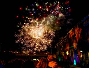 Spectators watch as fireworks explode over Memorial Field in downtown Port Townsend on Saturday night to herald in the new year. The fireworks, set to go off at 9 p.m. to coincide with the Times Square celebration in New York City, were the concluding event of First Night, an all-ages New Years Eve event put on by The Production Alliance, a non-profit in Port Townsend. Madison Street, site of city hall on the right, was blocked off so people could watch the display unhindered by traffic. (Steve Mullensky/for Peninsula Daily News)