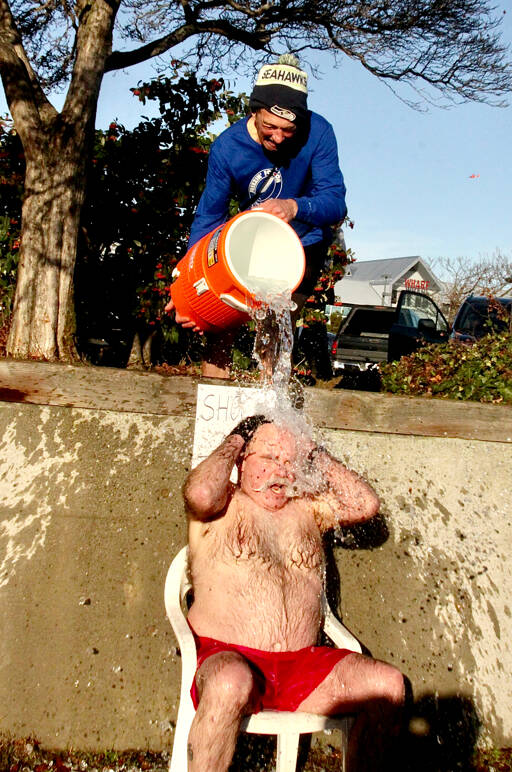 Event organizer Dan Welden, top, pours ice-filled water over Bruce Monro of Port Angeles as a part of a fundraiser for Volunteer Hospice of Clallam County at Hollywood Beach. The theme of the annual event this year was Shock and Thaw. (Dave Logan/for Peninsula Daily News)
