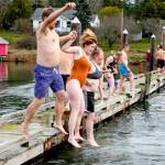 From left, Kevin Frary and Katie Oman of Marrowstone Island and Casey Frary of Washington, D.C., jump as a family into Mystery Bay to take part in the annual Polar Bear Plunge at the Nordland General Store on Sunday. About 50 people took part in the event. (Steve Mullensky/for Peninsula Daily News)