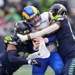 Los Angeles Rams quarterback Baker Mayfield, center, is tackled by Seattle Seahawks linebackers Bruce Irvin, right, and Uchenna Nwosu during the second half of an NFL football game Sunday, Jan. 8, 2023, in Seattle. (AP Photo/Stephen Brashear)