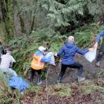 Members of 4PA, along with a handful of other volunteers, form a human chain to ferry bags of garbage and other debris from a homeless camp in Tumwater Creek to waiting trucks along the Tumwater Truck Route in Port Angeles on Saturday. Nearly two dozen people took part in the effort to clean up areas along the creek and adjoining woods. (Keith Thorpe/Peninsula Daily News)