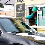 Andie Spencer, a barista at the Lincoln Street Coffee Pot in Port Angeles, hands a drink order to a customer in a snow-covered car on Wednesday after the city received a dusting of snow overnight at sea level. Higher elevations reported up to 2 inches of snow. Areas across the North Olympic Peninsula, including in Forks and Port Townsend, received little snow overnight. Scattered periods of snow with cold temperatures are expected into early next week across the Peninsula. (Keith Thorpe/Peninsula Daily News)