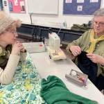 Loran Scruggs, left, brought a green cashmere sweater, a pair of floral silk pants and a pair of black cotton pants that needed to be mended to the Port Townsend Marine Science Centers Repair Cafe. Paula Lalish was one of three volunteers on hand to assist people by fixing clothing that had holes, rips, tears and and broken zippers. (Paula Hunt/Peninsula Daily News)
