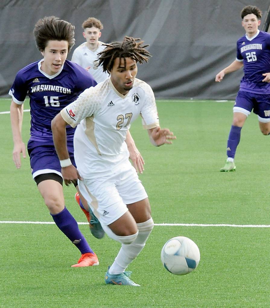 Peninsulas Abdurahim Leigh, center, evades the defense of the University of Washingtons Jack Maguire on Saturday in Port Angeles. (Keith Thorpe/Peninsula Daily News)