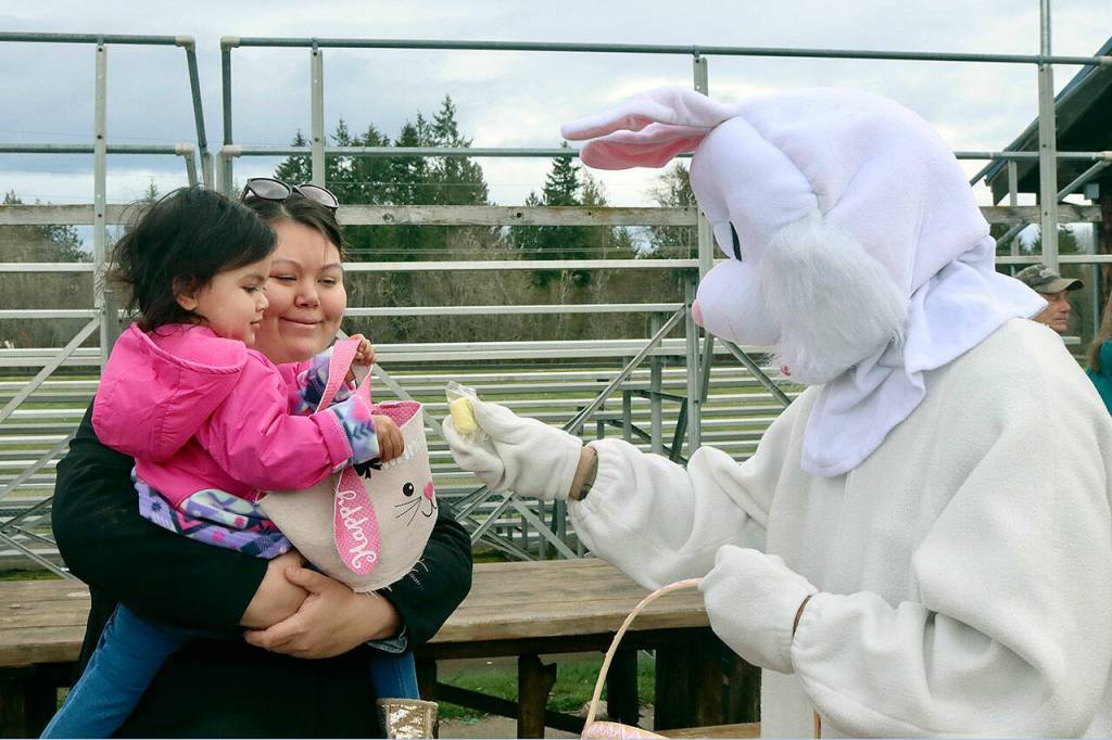 Annalise Sanchez, 2 1/2, gets a prehunt candy from the Easter bunny, Stefano Perruccio. Mom, Eyvonne Bolstrom, is all smiles. The 20th Kitchens Family Easter Egg Hunt had three divisions for kids 3 and younger, 4-6 and 8-12 on separate parts of the Crescent School playground and football field. The Kitchens family prepared 2,500 plastic eggs and 480 boiled eggs for the children to hunt. (Dave Logan/for Peninsula Daily News)