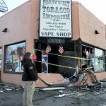Justin Brophy, general manager of Northwest Tobacco Emporium, at 309 E. First St. in Port Angeles, examines the front of the establishment on Wednesday morning after a car crashed into the building and caught fire late Tuesday night. (Keith Thorpe/Peninsula Daily News)