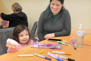 Arya Morrison, 3, grins while creating an art project as her mother, Janeth Morrison of Port Angeles, looks on during Saturdays Dia del Niño, or Day of the Child, at the Port Angeles Public Library. The event, based upon an annual celebration in Mexico, was created to recognize the importance of children in society and to promote youth literacy. (Keith Thorpe/Peninsula Daily News)