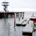 Port Angeles Parks and Recreation Department workers prepare floating dock sections for installation after they were barged across Port Angeles Harbor from storage to Port Angeles City Pier on Thursday. The docks, used for transient moorage, have not been deployed since 2021, when a primary float was damaged by a storm. Floats are scheduled to be in place this weekend, although the gangways from the upper pier deck will not be lowered into position until next week. The utility vessel Cheyenne Arrow assisted with bringing the sections across the harbor. (Keith Thorpe/Peninsula Daily News)