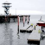 Port Angeles Parks and Recreation Department workers prepare floating dock sections for installation after they were barged across Port Angeles Harbor from storage to Port Angeles City Pier on Thursday. The docks, used for transient moorage, have not been deployed since 2021, when a primary float was damaged by a storm. Floats are scheduled to be in place this weekend, although the gangways from the upper pier deck will not be lowered into position until next week. The utility vessel Cheyenne Arrow assisted with bringing the sections across the harbor. (Keith Thorpe/Peninsula Daily News)