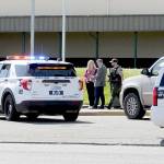 Port Angeles School District Assistant Superintendent Michelle Olsen, left, and Superintendent Marty Brewer, center, confer in front of Port Angeles High School as an armed Clallam County sheriffs deputy patrols the area after telephone threats were made to the school on Thursday. (Keith Thorpe/Peninsula Daily News)