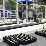 KEITH THORPE/PENINSULA DAILY NEWS
Riley Peterson of R & R Construction of Carbonado applies adhesive to the concrete base surrounding the playground equipment at Shane Park on Tuesday in Port Angeles in preparation for the replacement of cushioned tiles that make up the play surface. The rubberized tiles began to become loose in 2022 due to shrinkage and weather, forcing the playground's closure in September of that year.  The project, which will use as many of the original tiles as can be salvaged intermixed with new replacement tiles and new adhesive, is expected to be completed by mid-June.