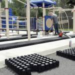 Riley Peterson of R & R Construction of Carbonado applies adhesive to the concrete base surrounding the playground equipment at Shane Park on Tuesday in Port Angeles in preparation for the replacement of cushioned tiles that make up the play surface. (KEITH THORPE/PENINSULA DAILY NEWS)