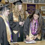 Quilcene High School graduate Rhiannon Chapman, right, puts the finishing touches on her mortar board while Ashley Jones, center, and Zoey Carver, left, watch. The trio were waiting for their graduation ceremony to start on Saturday at the high school. (Steve Mullensky/for Peninsula Daily News)
