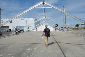 KEITH THORPE/PENINSULA DAILY NEWS
Steve Hargis, a board member of the Port Angeles Chamber of Commerce, directs the alignment of an events tent on Thursday that will cover a temporary roller skating rink in downtown Port Angeles.