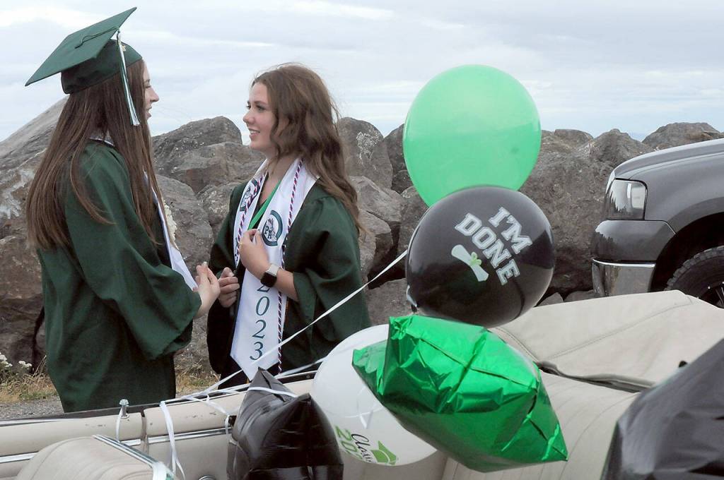Port Angeles High School graduates Frankie Williams, left, and Jacklyn Minnoch chat on Ediz Hook before Fridays graduation parade through the streets of Port Angeles. About 100 vehicles with graduates, family and friends took part in the procession from Ediz Hook to Port Angeles High School. (Keith Thorpe/Peninsula Daily News)