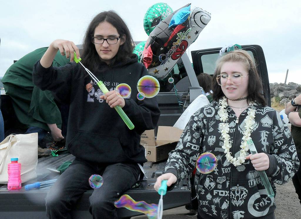 Port Angeles High School graduates Christopher Brown, left, and Kaelyn Herring play with bubbles prior to the start of Fridays Graduation Parade. About 100 vehicles with graduates, family and friends took part in the procession from Ediz Hook to Port Angeles High School. (Keith Thorpe/Peninsula Daily News)