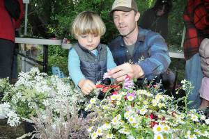 Noah Erickson, 2, snips a flower head with the help of his father, Chris Erickson of Port Angeles, while making a solstice crown headdress during the Summertide Solstice Art Festival on Saturday at the Port Angeles Fine Arts Center and adjoining Websters Woods Sculpture Park. The event served as a celebration of the coming of summer with a variety of food, music and outdoor activities. (Keith Thorpe/Peninsula Daily News)