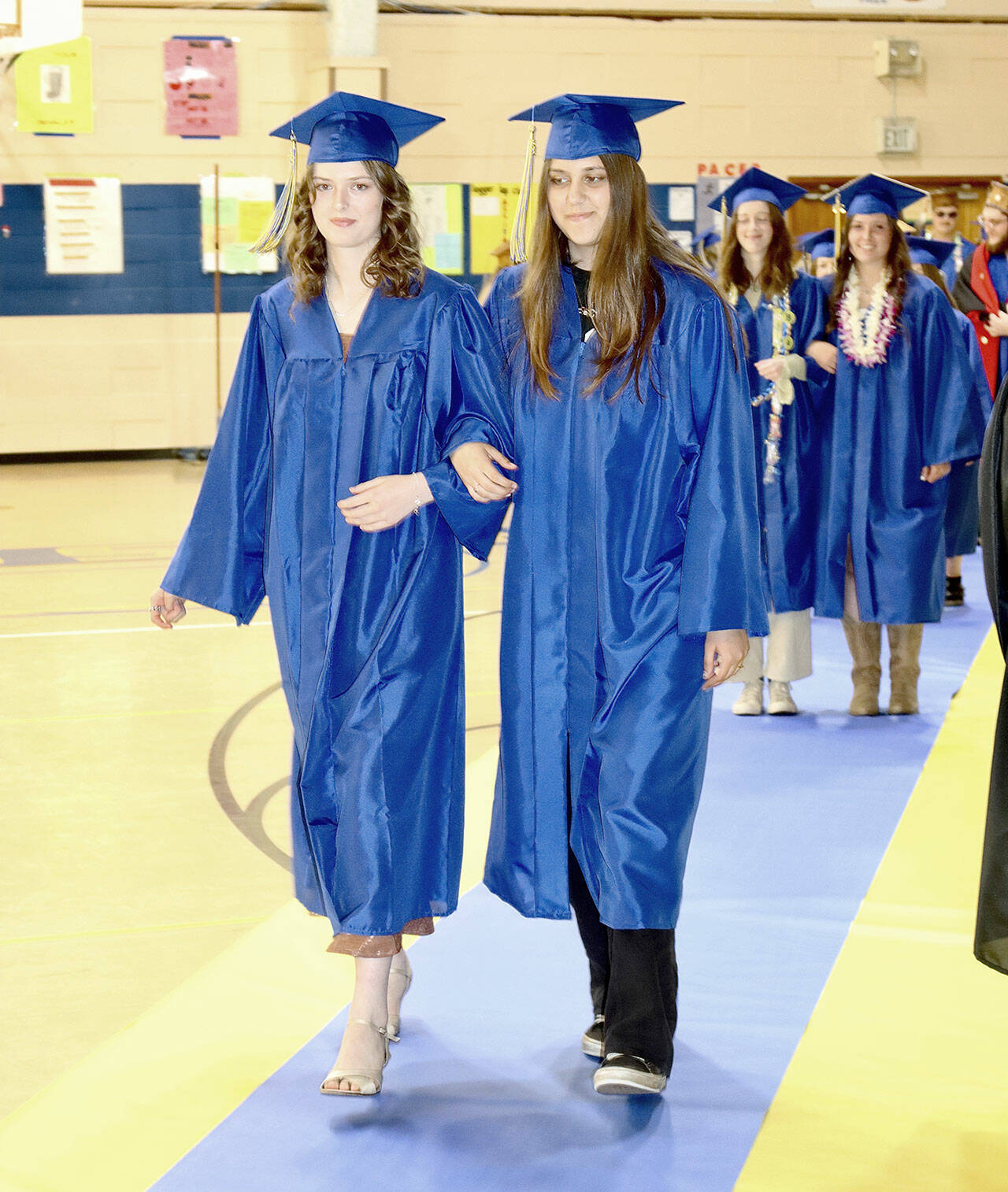 Leading the march of the 21 Crescent High School graduates are Harmony Henderson, left, and Rhylin Lium. Superintendent David Bingham presented the graduating class in front of a full house of family and friends in the high school gym. (Dave Logan/for Peninsula Daily News)