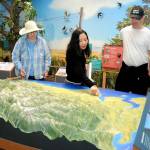 Dungeness River Nature Center visitors, from left, Chris McDonald of Port Angeles, Tram Pham of Huntington Beach, Calif., and Paul McDonald of Redmond examine a relief map display of the Dungeness River Watershed on Wednesday in Sequim. (KEITH THORPE/PENINSULA DAILY NEWS)