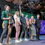Joel Savoy, left, outgoing Centrum Fiddle Tunes Artistic Director, reacts as a confetti noisemaker goes off behind him after he introduces the group The Onlies as the new artistic director and the first time a group has been selected for that position. The Onlies are a group of old friends who grew up playing fiddles, guitars and banjos in their hometowns of Seattle and Lexington, Va. Next to Savoy are Sami Braman, Riley Calcagno, Vivian Leva and Leo Shannon. Centrum staffer Peter McCracken is behind them. (Steve Mullensky/for Peninsula Daily News)