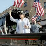 Port of Port Angeles Commissioner Colleen McAleer prepares to toss goodies to the crowd from the back of a trailered boat during Tuesdays Independence Day parade in Port Angeles. McAleer, along with fellow commissioners Steve Burke and Connie Beauvais, facing the other side, were the parades grand marshals in honor of the 100th anniversary of the port. (Keith Thorpe/Peninsula Daily News)