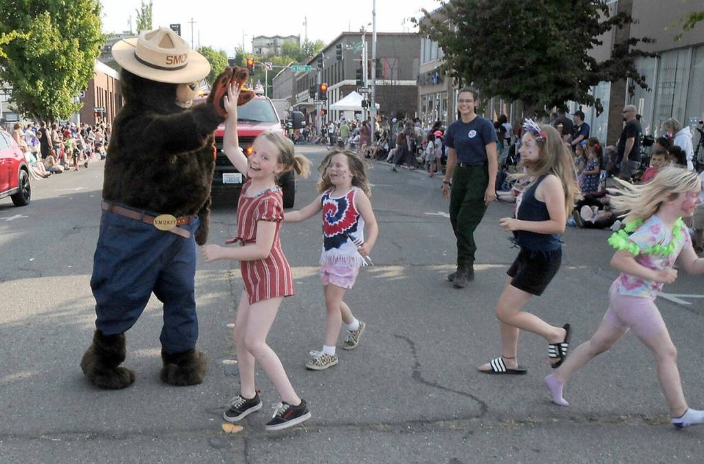 Smoky Bear, portrayed by state Department of Natural Resources employee Matt McBroom, is greeted by young parade-goers as fellow DNR employee Claire Lafrombois looks on during Tuesdays parade. (Keith Thorpe/Peninsula Daily News)