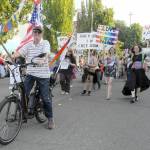 Lewis Bennett rides a decorated bicycle to lead the Fourth of July parade entry by the Peninsula Pride Patriots on Tuesday in downtown Port Angeles. (Keith Thorpe/Peninsula Daily News)