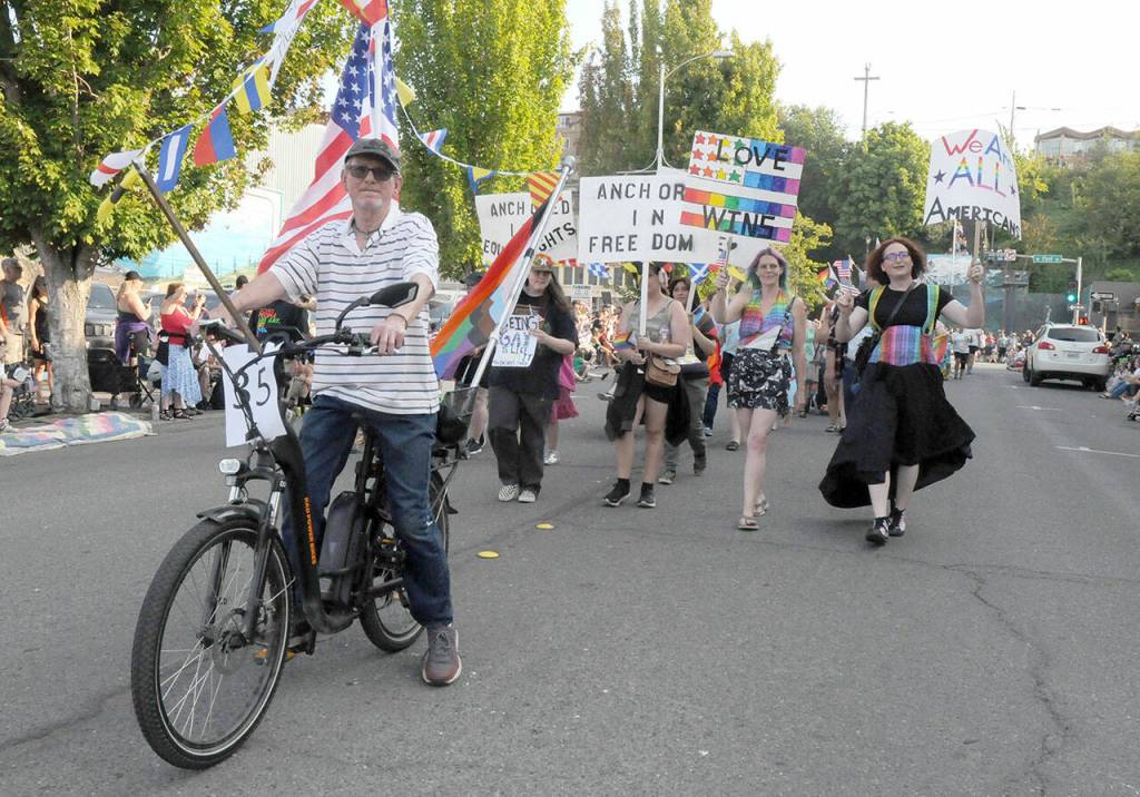 Lewis Bennett rides a decorated bicycle to lead the Fourth of July parade entry by the Peninsula Pride Patriots on Tuesday in downtown Port Angeles. (Keith Thorpe/Peninsula Daily News)