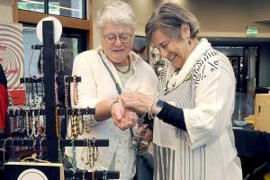 Carol Pearson of Sequim-based Lizzie Betz Jewelry assists Maureen Kennedy of Port Angeles with a bracelet during Saturdays Rain Shadow Artisans Fair at the Dungeness River Nature Center in Sequim. The event brought together more than a dozen local crafters with the opportunity to market their wares. (Keith Thorpe/Peninsula Daily News)