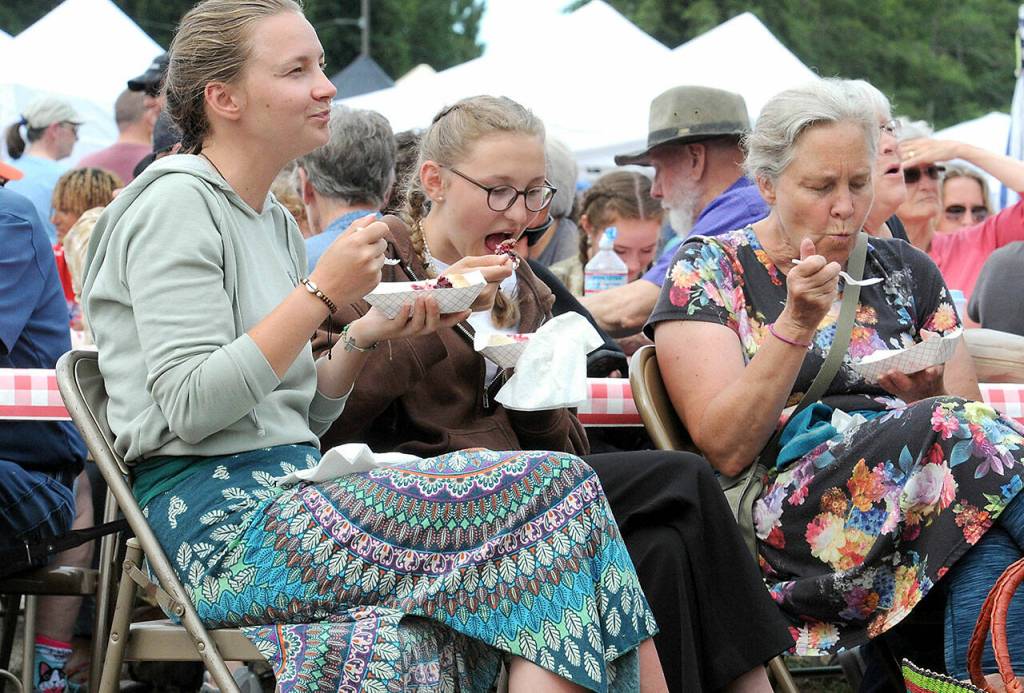 Joyce Daze Wild Blackberry Festival-goers, from left, Sarah Houtrouw of Rengshavsen, Germany, Nina Nusche of Fischwasser, Germany, and Sheriann Houtrouw of Freshwater Bay enjoy slices of blackberry pie on Saturday in Joyce. (Keith Thorpe/Peninsula Daily News)