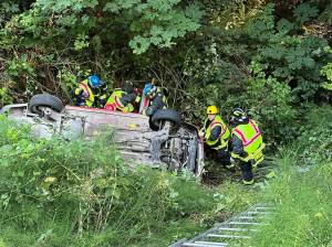 First responders prevent a vehicle from sliding farther down an embankment after it went off U.S. Highway 101 Monday evening. Its driver, a 61-year-old Sequim woman, died in the crash. (Clallam County Fire District 3)