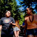 Serina Fast Horse, of Sicangu Lakota & Blackfeet Tribes, left, talks with Jacy Bowles, of Xicana and Diné descent, as they walk to the former Elwha Dam site during the 2023 Tribal Climate Camp on the Olympic Peninsula on Aug. 16 near Port Angeles. Participants representing at least 28 tribes and intertribal organizations gathered to connect and share knowledge as they work to adapt to climate change that disproportionally affects Indigenous communities. More than 70 tribes have taken part in the camps that have been held across the United States since 2016. (Lindsey Wasson/The Associated Press)