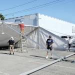 KEITH THORPE/PENINSULA DAILY NEWS
A work crew erects a tent in a city parking lot in the 100 block of West Front Street in downtown Port Angeles on Friday in preparation for Sunday's First Federal centennial celebration.