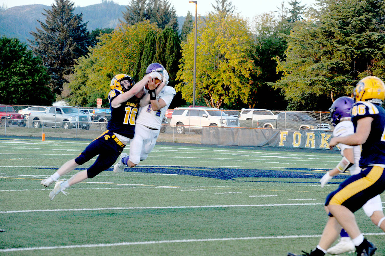 Forks Gunner Rogers (16) and Sequims Zeke Schmadeke (14) pull in a Forks pass for joint possession. Joint possession goes to the offense giving Forks a first down. (Lonnie Archibald/for Peninsula Daily News)