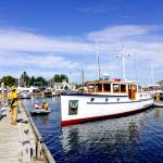 Riptide, a 47-foot wooden boat from Port Ludlow owned by Pete Leenhouts, built in 1927 by Schertzer Bros. of Seattle, is gently nudged to the dock by volunteer harbormasters on Thursday in preparation for todays opening of the 46th annual Wooden Boat Festival at Point Hudson Marina in Port Townsend. The festival runs through Sunday. (Steve Mullensky/for Peninsula Daily News)