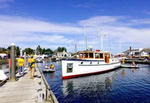 Riptide, a 47-foot wooden boat from Port Ludlow owned by Pete Leenhouts, built in 1927 by Schertzer Bros. of Seattle, is gently nudged to the dock by volunteer harbormasters on Thursday in preparation for todays opening of the 46th annual Wooden Boat Festival at Point Hudson Marina in Port Townsend. The festival runs through Sunday. (Steve Mullensky/for Peninsula Daily News)