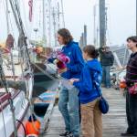Steve Mullensky/for Peninsula Daily News
Ocean Smith gets ready to hand off a vase of flowers to a Northwest Maritime Center sailing team member already aboard during an early Friday morning delivery of flowers purchased on Thursday. Looking on are teammates Ava Butterfield and Charley Capel.