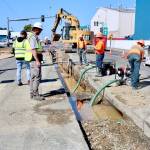 Weston Jorgensen, capital projects inspector, at left, watches as workers dewater a trench for a sewer main installation on Marine Drive at Tumwater Truck Route in Port Angeles after a water main was damaged Thursday morning. Work on the sewer main crossing at Tumwater Truck Route was expected to be finished on Thursday, but the water main damage slowed that work, according to city civil engineer Lucio Baack. He anticipated the Tumwater Truck Route traffic signal to be shut off temporarily today while the water main is repaired. The work is part of a larger project to install a new sewer force main for Pump Station 3. (Dave Logan/for Peninsula Daily News)