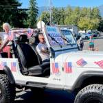 Quilcene Parade Grand Marshal Melody Bacchus waves to the crowd on Saturday, the unofficial kickoff to the annual fair. The Quilcene Oyster Half Marathon, 10K and 5K runs were held Sunday, and the arts and crafts show returned this year. (David Goetze)