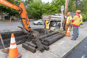 A crew from Port Townsend Public Works watches as a backhoe removes water-logged timber from a sinkhole on Kearney Street outside the Food Co-op on Tuesday at the start of construction of a traffic circle at the intersection of state Highway 20/East Sims Way and Kearney Street in Port Townsend. Traffic heading eastbound toward Port Townsend will detour at Benedict Street and turn left on Washington Street to return to Highway 20/East Sims Way. Traffic going westbound away from Port Townsend will turn right at Kearney Street and left onto Jefferson Street to continue on Highway 20. The detour configuration will last about four weeks, according to the state Department of Transportation. (Steve Mullensky/for Peninsula Daily News)
