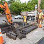 A crew from Port Townsend Public Works watches as a backhoe removes water-logged timber from a sinkhole on Kearney Street outside the Food Co-op on Tuesday at the start of construction of a traffic circle at the intersection of state Highway 20/East Sims Way and Kearney Street in Port Townsend. Traffic heading eastbound toward Port Townsend will detour at Benedict Street and turn left on Washington Street to return to Highway 20/East Sims Way. Traffic going westbound away from Port Townsend will turn right at Kearney Street and left onto Jefferson Street to continue on Highway 20. The detour configuration will last about four weeks, according to the state Department of Transportation. (Steve Mullensky/for Peninsula Daily News)