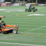 Tim Morland, front, and Rich Lear of Tualatin, Ore.-based Field Turf USA add fill to the playing surface at the new Monroe Athletic Field on Tuesday at the site of the former Monroe School near Roosevelt Elementary School in Port Angeles. The synthetic turf field, which is expected to be completed by mid-autumn, is being developed by the Port Angeles School District and will be available for community athletic events. (Keith Thorpe/Peninsula Daily News)